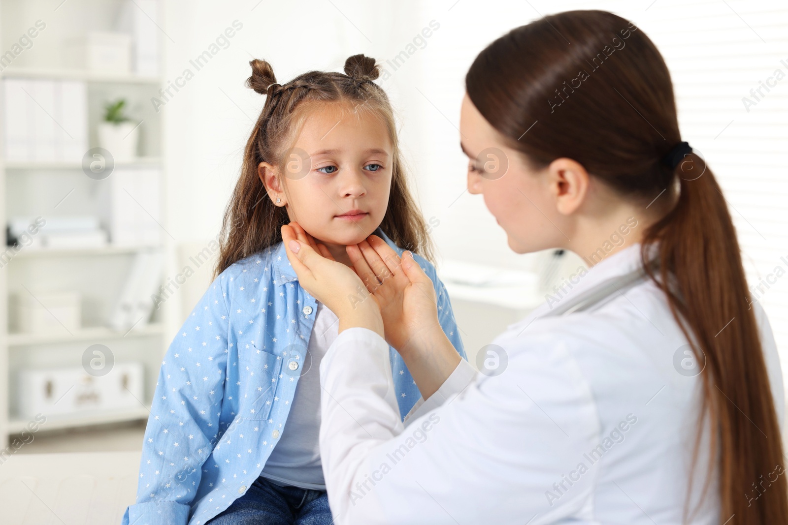 Photo of Doctor examining girl's throat in clinic during appointment