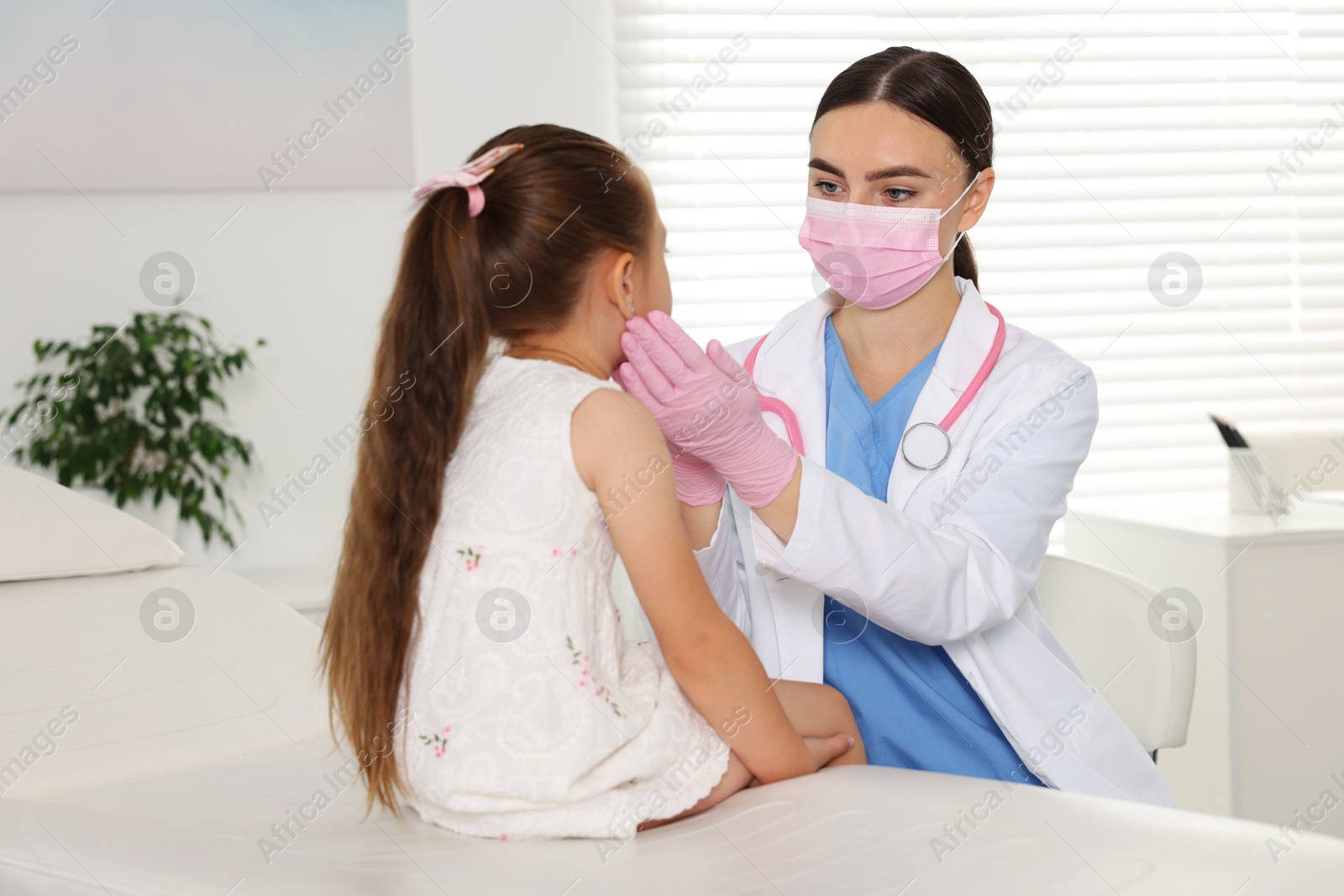 Photo of Doctor examining girl's throat in clinic during appointment