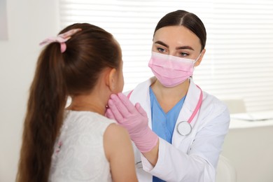 Photo of Doctor examining girl's throat in clinic during appointment