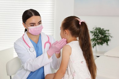 Photo of Doctor examining girl's throat in clinic during appointment