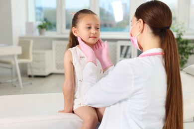 Photo of Doctor examining girl's throat in clinic during appointment