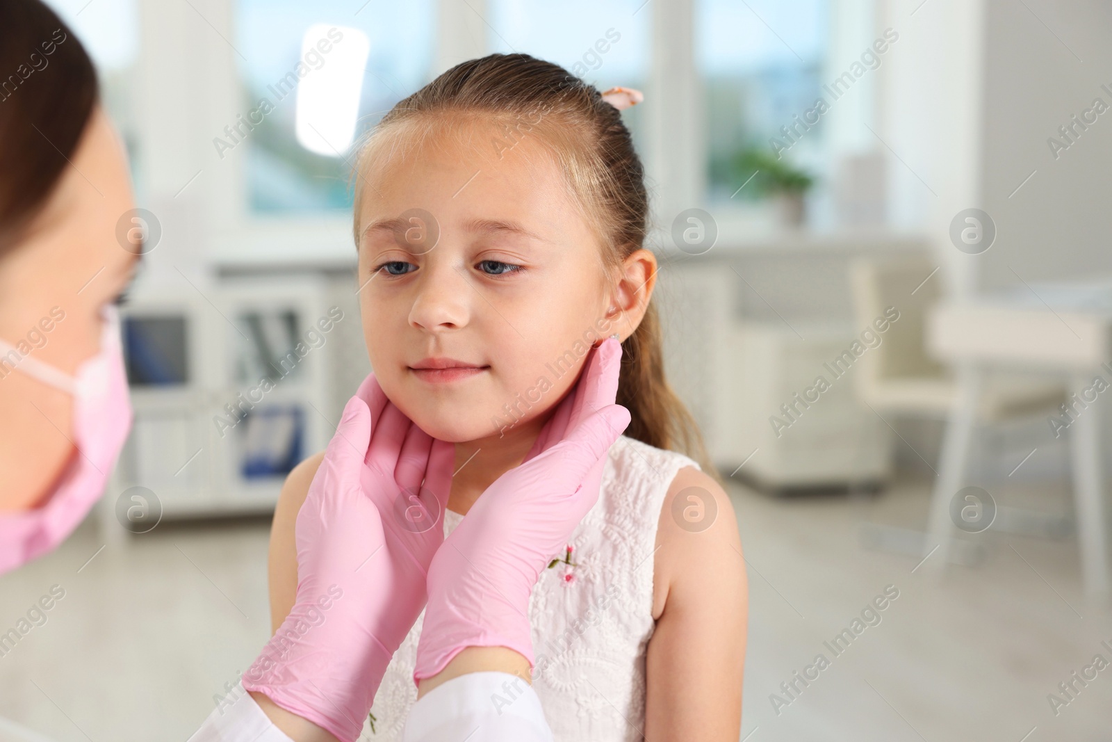 Photo of Doctor examining girl's throat in clinic during appointment