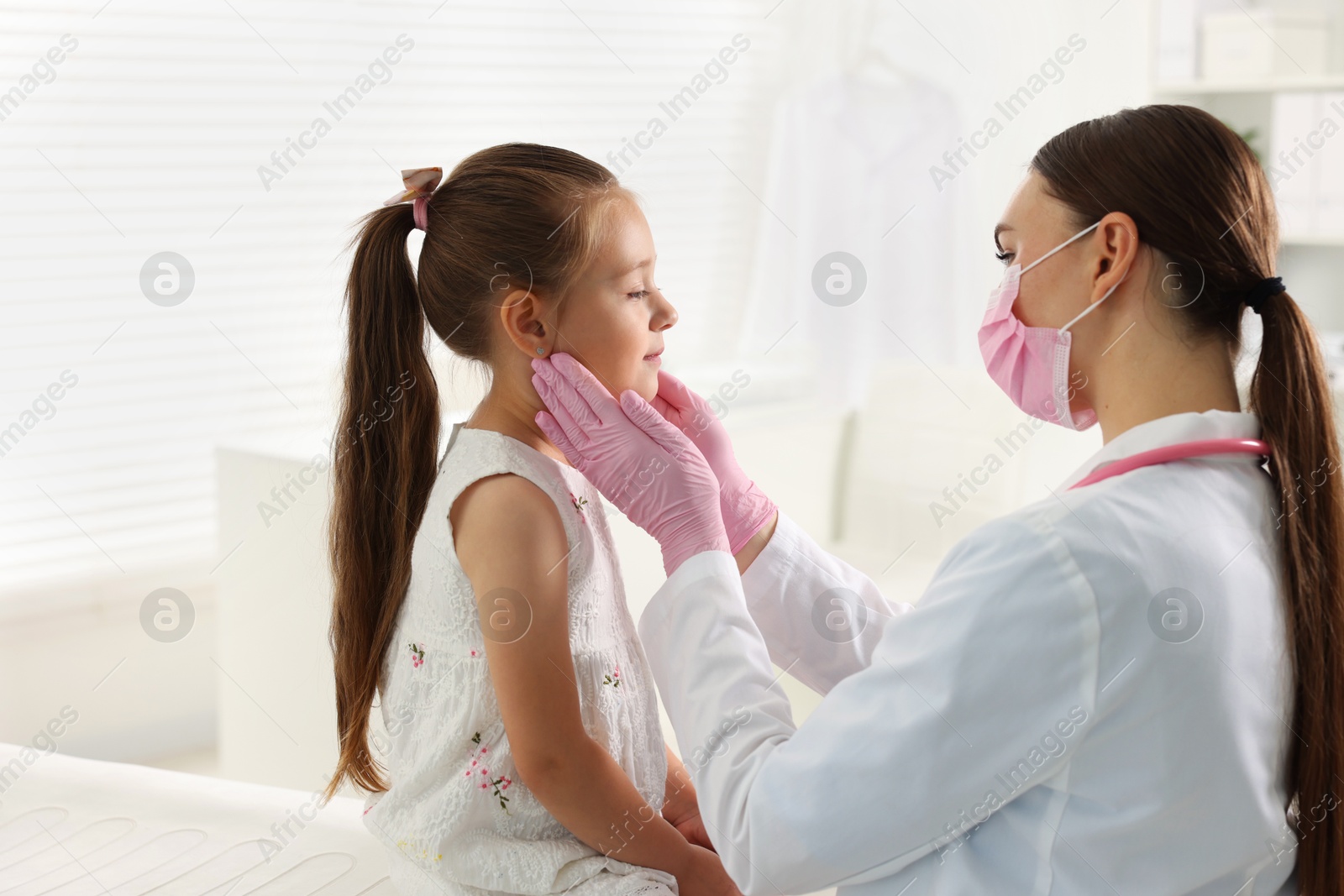 Photo of Doctor examining girl's throat in clinic during appointment