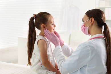 Photo of Doctor examining girl's throat in clinic during appointment