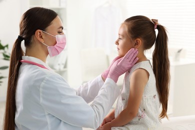 Photo of Doctor examining girl's throat in clinic during appointment