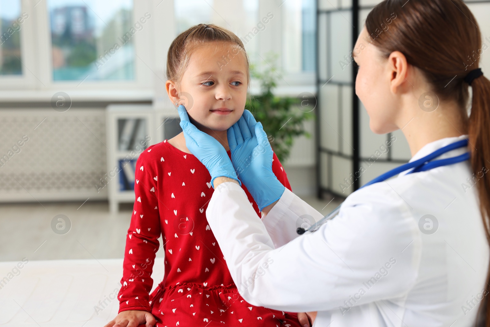 Photo of Doctor examining girl's throat in clinic during appointment