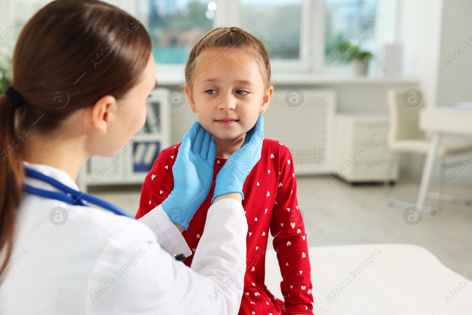 Photo of Doctor examining girl's throat in clinic during appointment