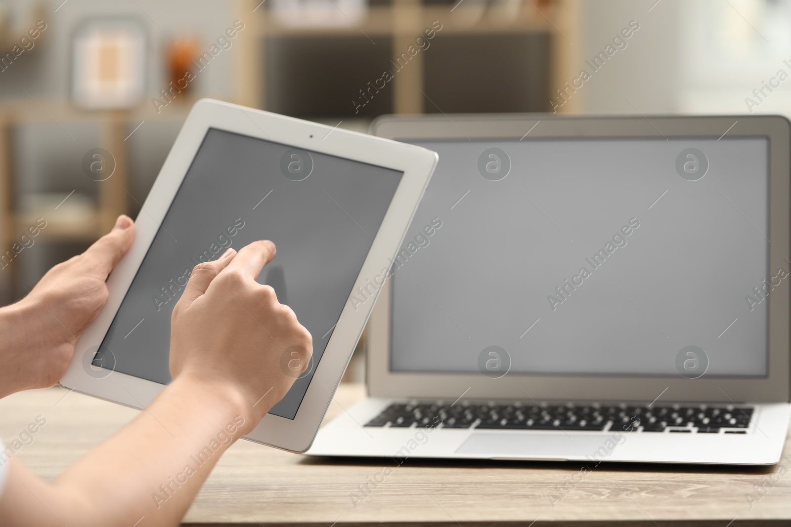 Photo of Businessman with tablet and laptop at wooden table, closeup. Modern technology