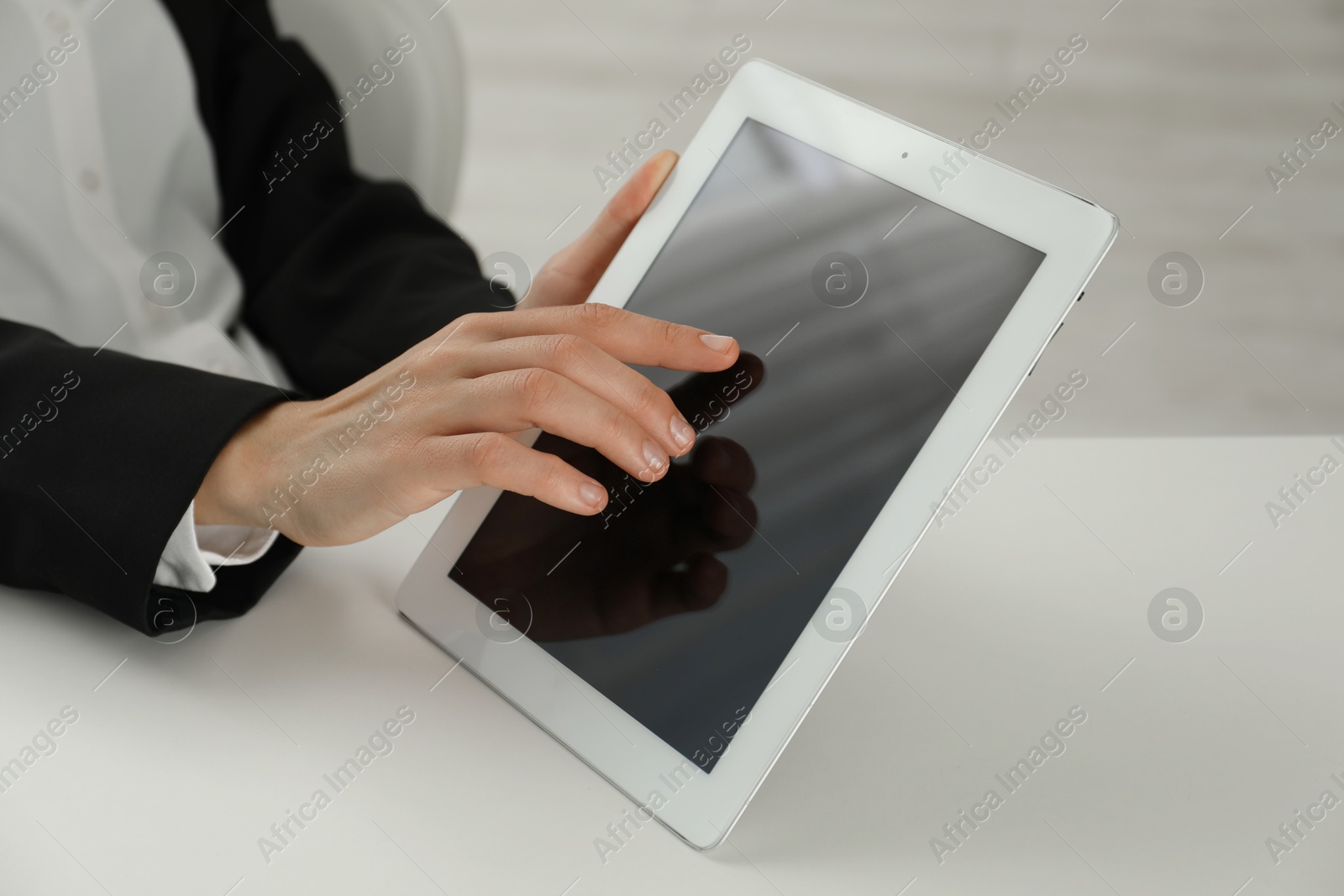 Photo of Businesswoman using tablet at white table indoors, closeup. Modern technology