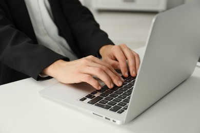 Photo of Businesswoman using laptop at white table indoors, closeup. Modern technology