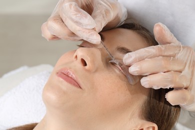 Eyelash lamination procedure. Esthetician sticking woman's lashes to pad in beauty salon, closeup