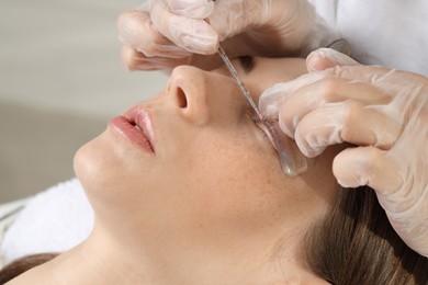 Photo of Eyelash lamination procedure. Esthetician sticking woman's lashes to pad in beauty salon, closeup