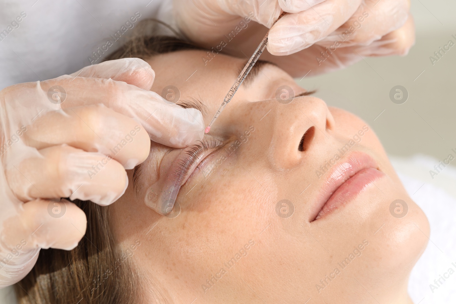 Photo of Eyelash lamination procedure. Esthetician sticking woman's lashes to pad in beauty salon, closeup