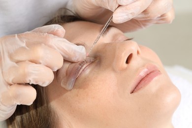 Photo of Eyelash lamination procedure. Esthetician sticking woman's lashes to pad in beauty salon, closeup