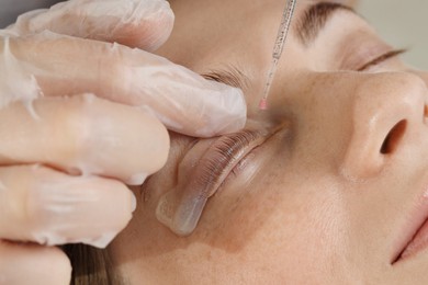 Photo of Eyelash lamination procedure. Esthetician sticking woman's lashes to pad in beauty salon, closeup