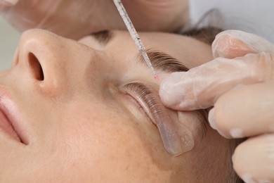 Eyelash lamination procedure. Esthetician sticking woman's lashes to pad in beauty salon, closeup