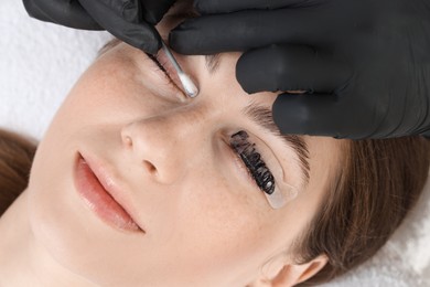 Eyelash lamination procedure. Esthetician wiping dye from woman's lashes in beauty salon, closeup