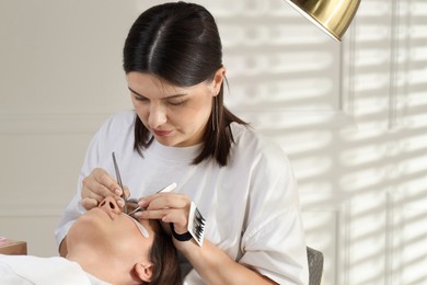 Esthetician applying lash extensions on natural ones in beauty salon