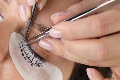 Photo of Young woman undergoing lash extensions procedure, closeup