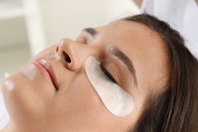 Photo of Young woman undergoing lash extensions procedure in beauty salon, closeup