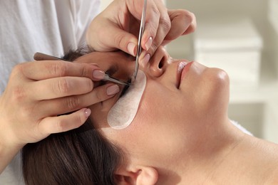 Photo of Woman undergoing lash extensions procedure in beauty salon, closeup