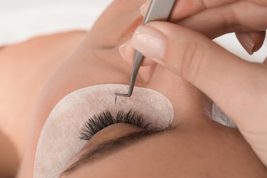 Photo of Young woman undergoing lash extensions procedure, closeup