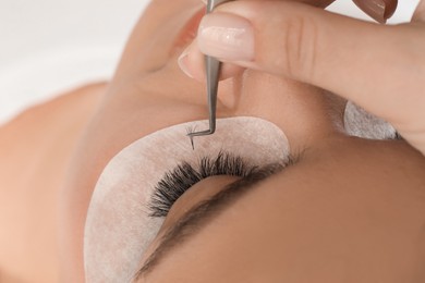 Photo of Young woman undergoing lash extensions procedure, closeup