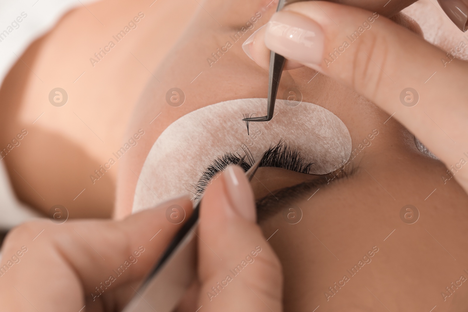 Photo of Young woman undergoing lash extensions procedure, closeup