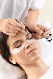 Woman undergoing lash extensions procedure in beauty salon, closeup