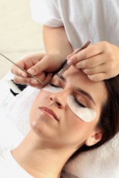 Woman undergoing lash extensions procedure in beauty salon, closeup