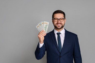 Photo of Portrait of banker with dollar banknotes on grey background, space for text