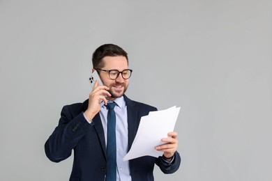 Photo of Banker with documents talking on smartphone against grey background. Space for text