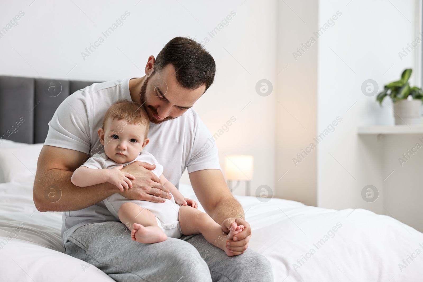 Photo of Father with his little baby on bed at home. Space for text