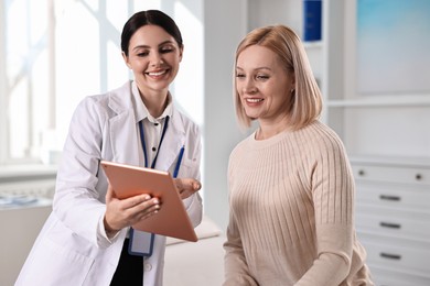 Doctor with tablet consulting woman in clinic