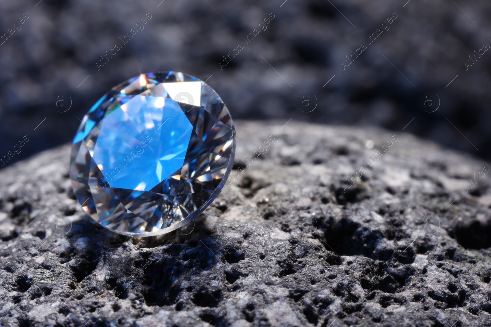 Photo of Beautiful shiny gemstone on stone, closeup. Space for text