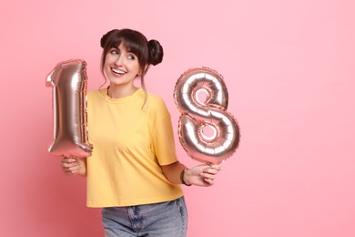 Photo of Coming of age party - 18th birthday. Young woman holding number shaped balloons on pink background, space for text