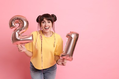 Photo of Coming of age party - 21st birthday. Young woman holding number shaped balloons on pink background, space for text