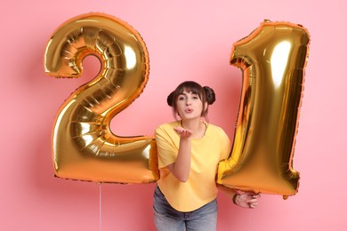 Photo of Coming of age party - 21st birthday. Young woman holding number shaped balloons on pink background