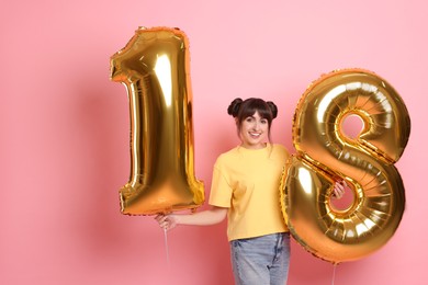 Photo of Coming of age party - 18th birthday. Young woman holding number shaped balloons on pink background