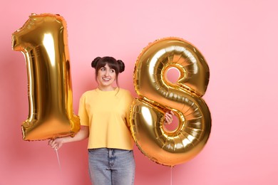 Photo of Coming of age party - 18th birthday. Young woman holding number shaped balloons on pink background