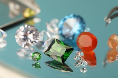 Photo of Beautiful colorful gemstones on mirror surface, closeup