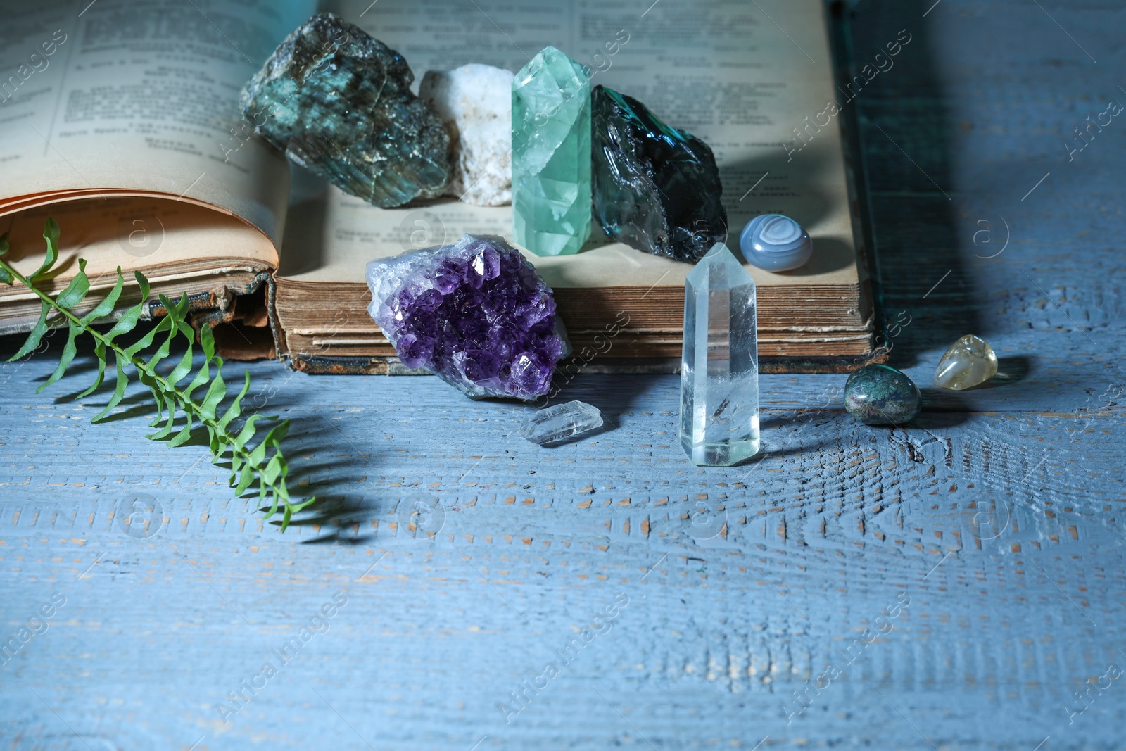 Photo of Beautiful natural gemstones and book on grey table, closeup