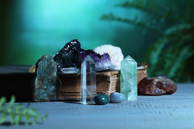 Photo of Beautiful natural gemstones and book on grey table against green background