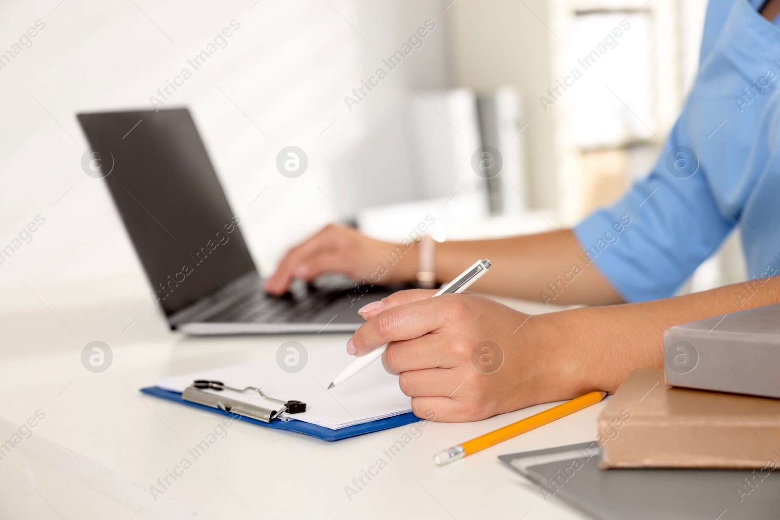 Photo of Medical student studying with laptop at table indoors, closeup