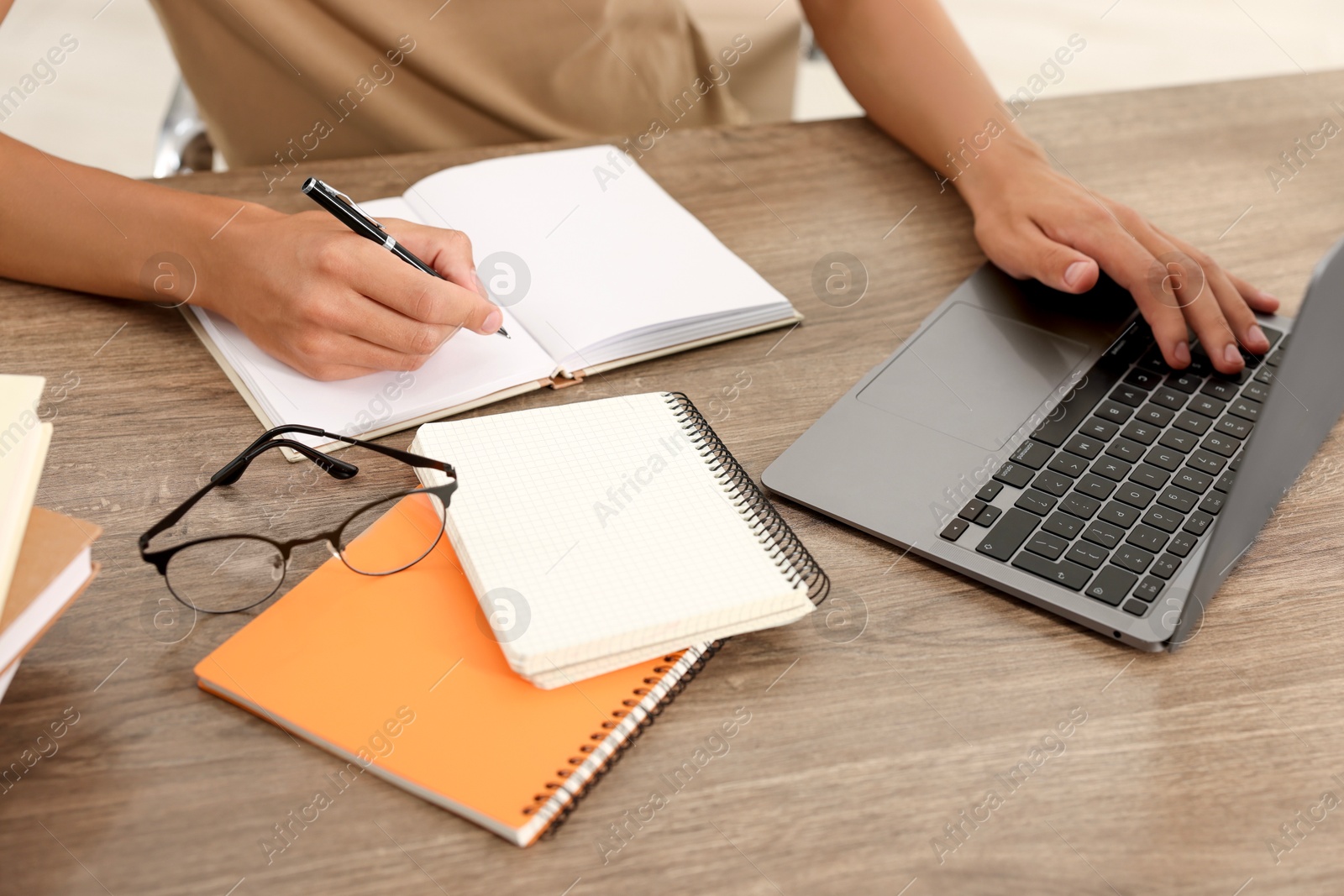 Photo of Student studying with laptop at wooden table indoors, closeup