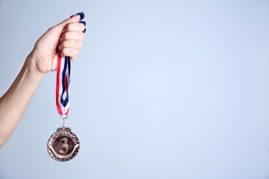 Photo of Woman with bronze medal on grey background, closeup. Space for text