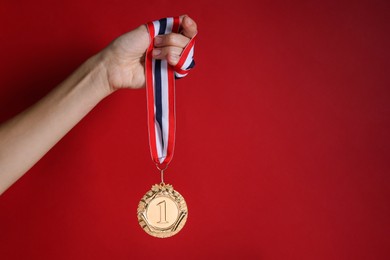 Photo of Woman with golden medal on red background, closeup. Space for text