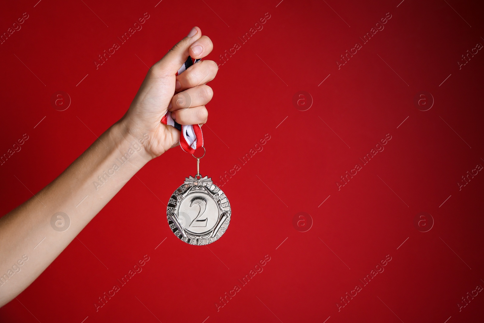 Photo of Woman with silver medal on red background, closeup. Space for text