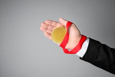 Photo of Man with golden medal on grey background, closeup. Space for text