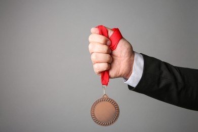 Photo of Man with bronze medal on grey background, closeup. Space for text